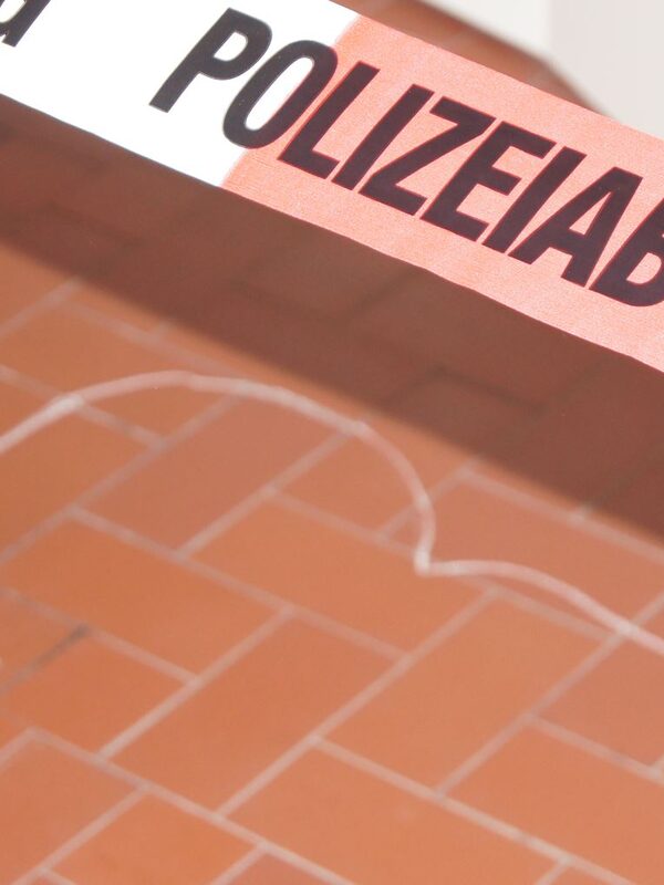 Ein Polizeiabsperrband über einen auf dem Boden mit Kreide gezeichneten Kopf