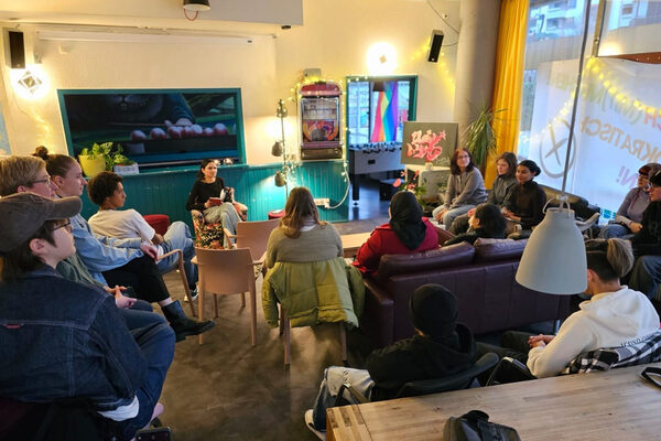 Mehrere Menschen sitzen zusammen auf Sofas und Stühlen.